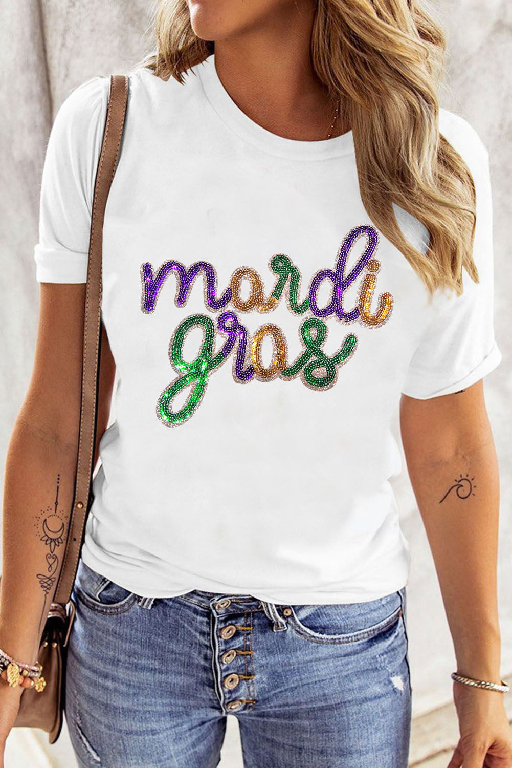 Person wearing a white t-shirt with 'mardi gras' text in colorful letters.