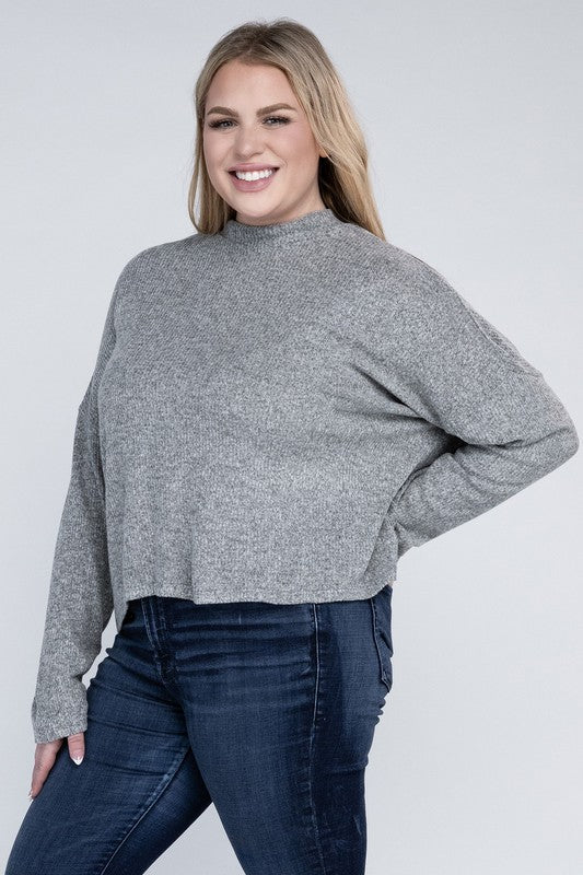 Woman wearing a gray sweater and blue jeans against a white background