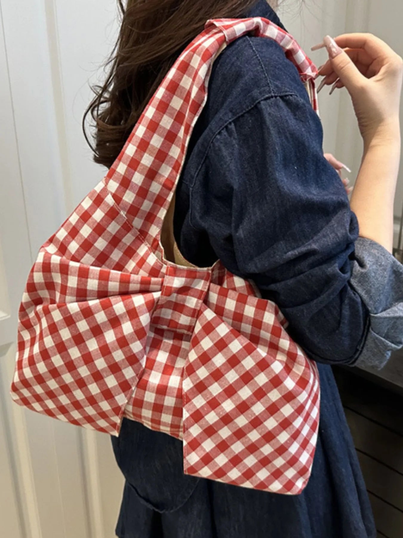 Person wearing a red and white checkered bag over their shoulder with a plain background