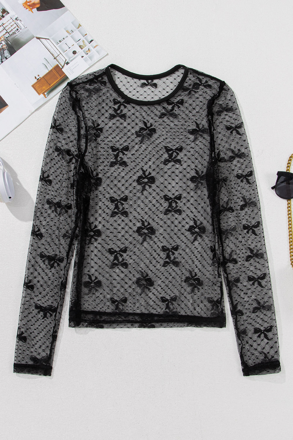 Black lace long-sleeve top with bow pattern on a white surface