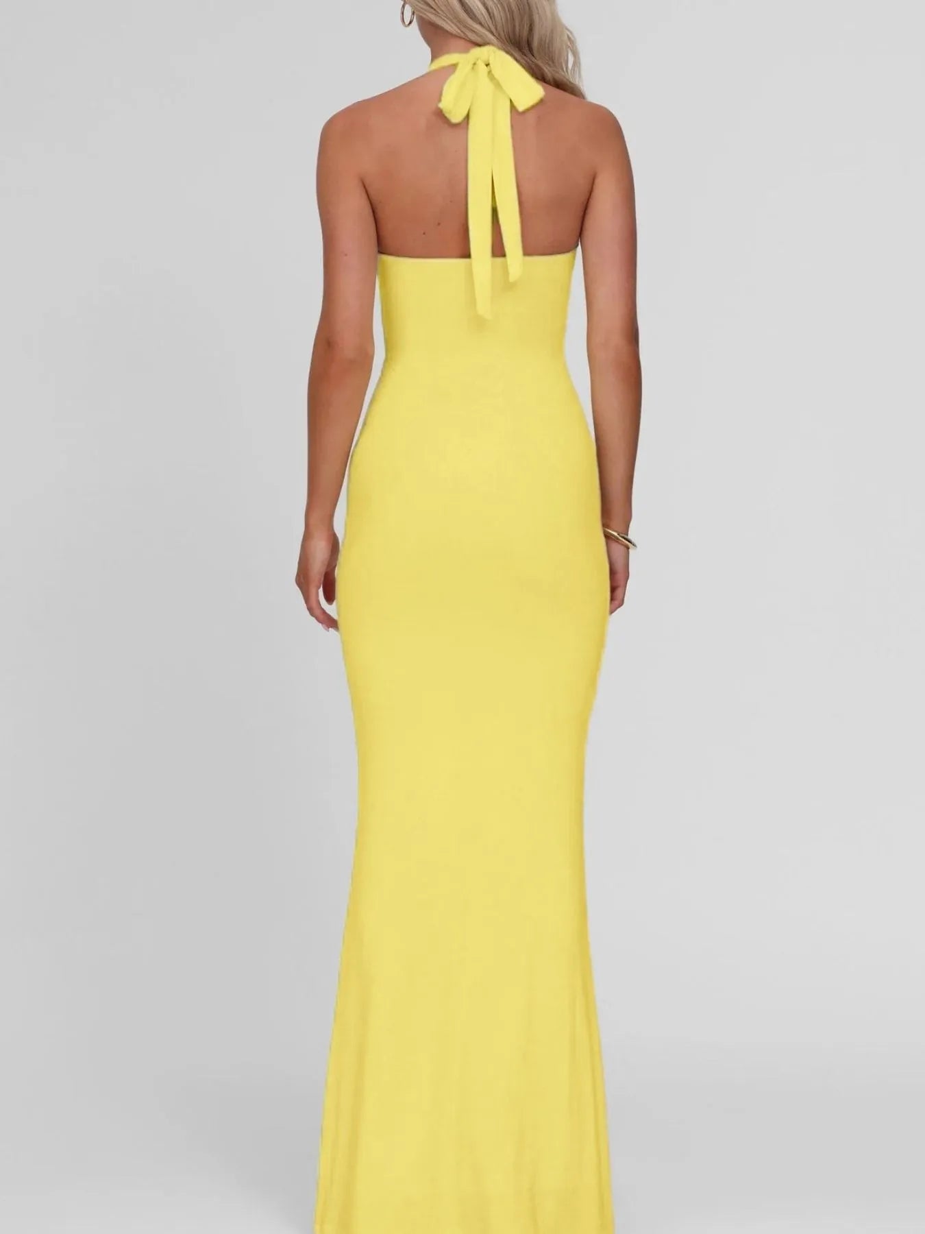 Yellow halter neck gown on a plain background