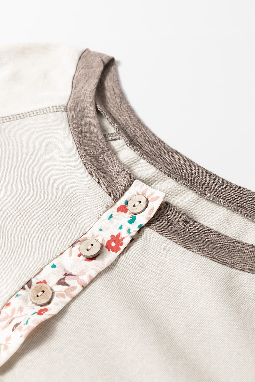 Floral strap with buttons on a beige garment against a white background