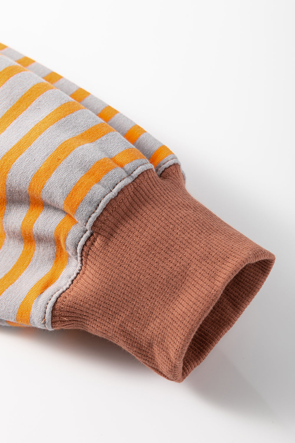 Close-up of a sleeve with orange and gray striped pattern on a white background
