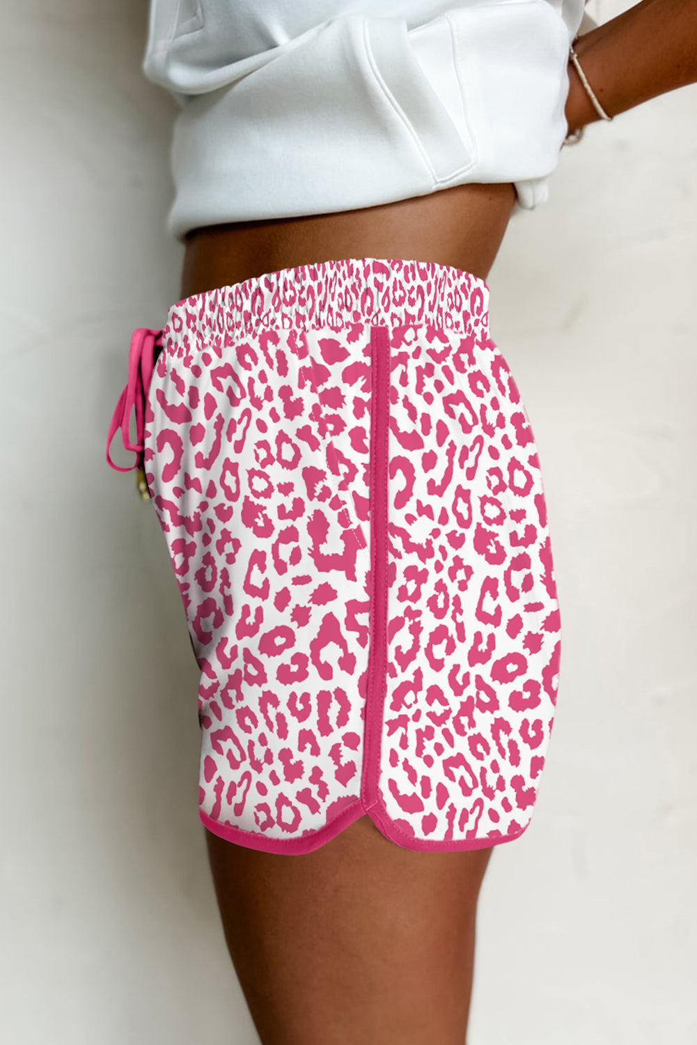 Pink leopard print shorts worn by a person on a plain background
