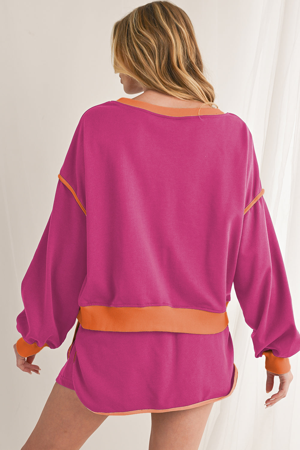 Person wearing a pink outfit with orange accents on a plain background