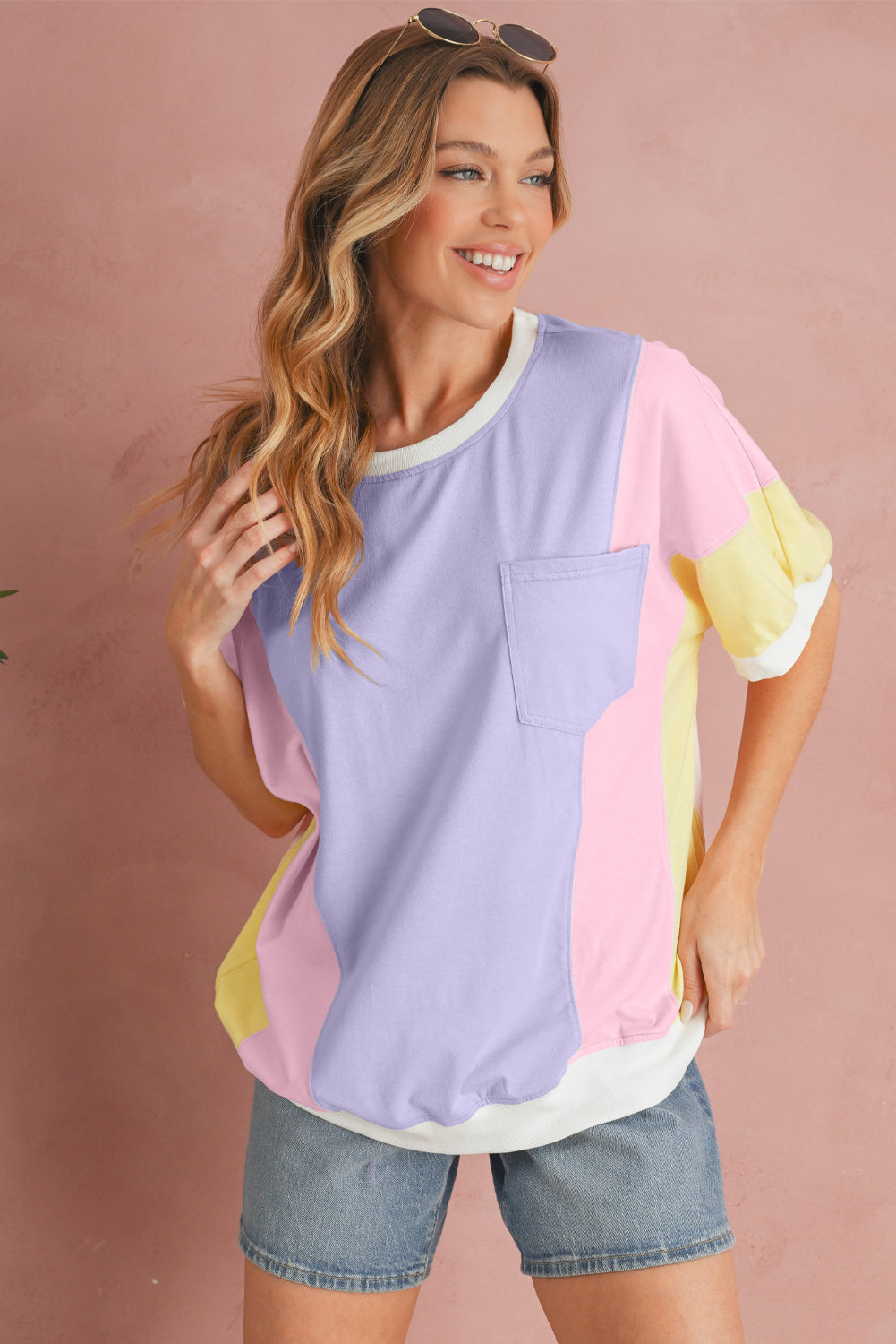 Woman wearing a colorful shirt with a pink, yellow, and purple design on a pink background