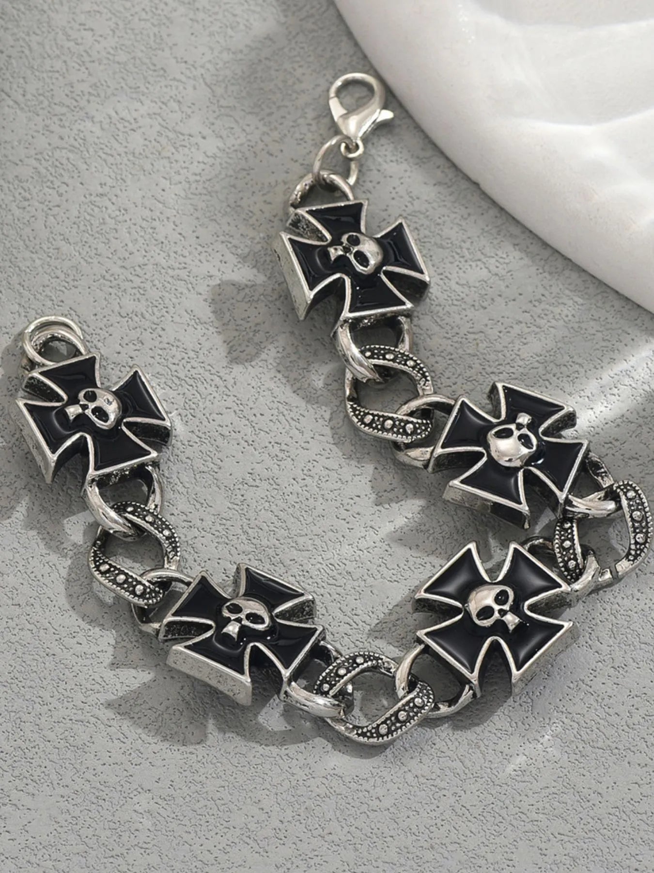 Silver bracelet with black bow-shaped charms on a gray surface