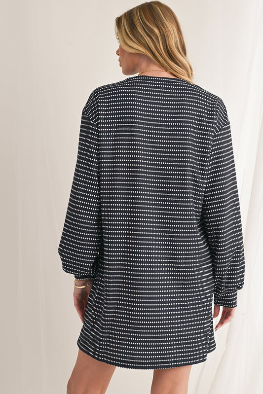 Woman wearing a black and white patterned dress against a neutral background