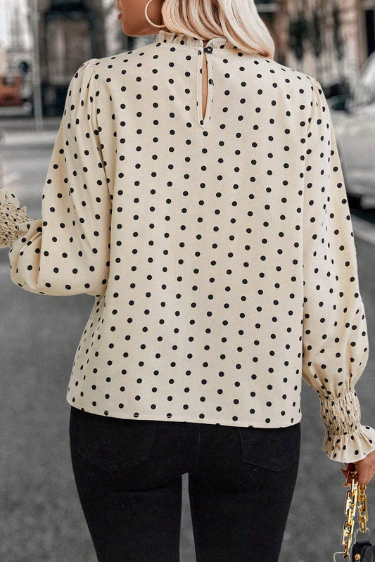 Person wearing a polka dot blouse with long sleeves in an urban setting