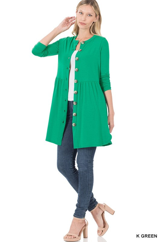 Woman wearing a green cardigan over a white top and blue jeans on a white background