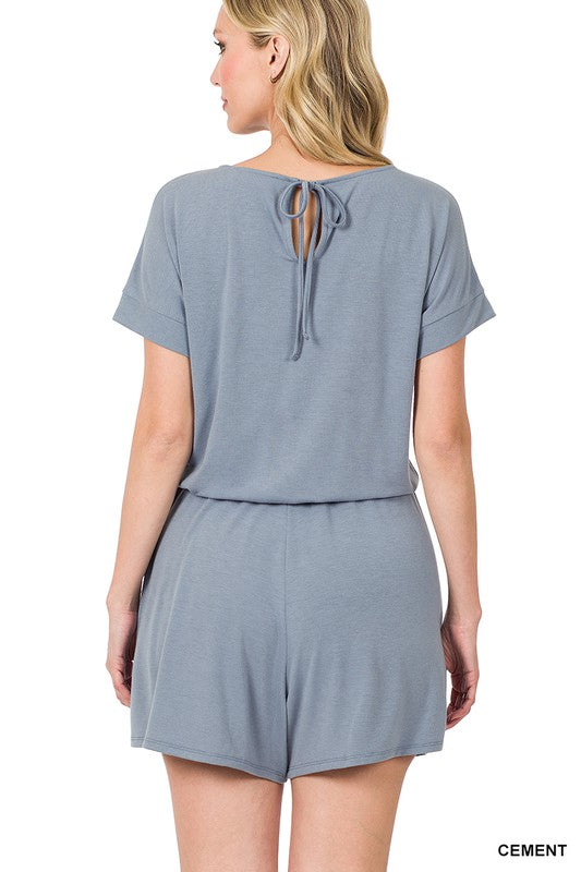 Woman wearing a gray romper with a tie-back detail on a white background