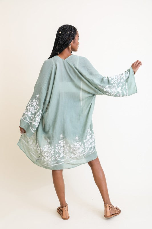 Woman wearing a light blue embroidered dress against a white background