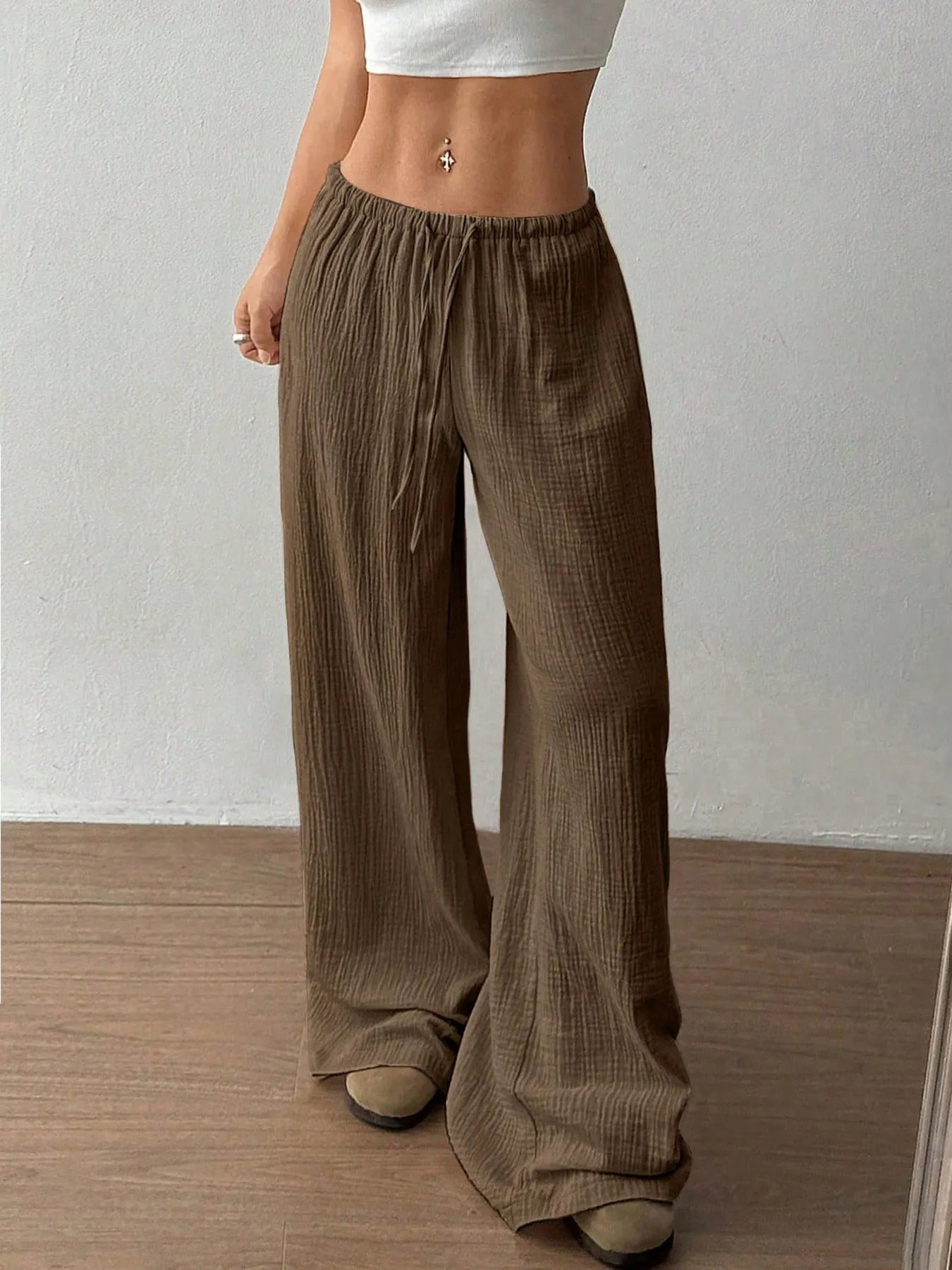 Person wearing brown wide-leg pants against a plain background