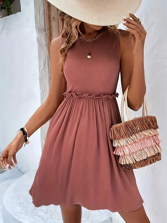 Woman wearing a rust-colored dress with a straw hat and ruffled handbag against a white background