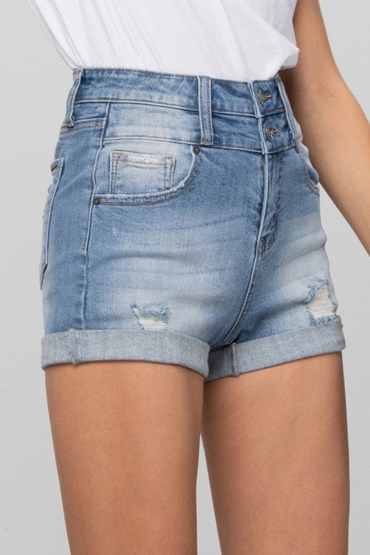 Blue denim shorts worn by a person on a plain background