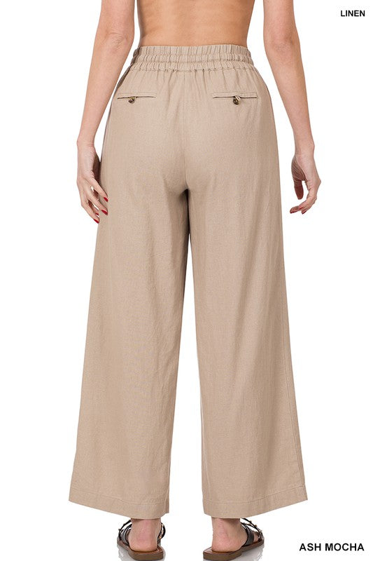 Beige linen pants worn by a model on a white background