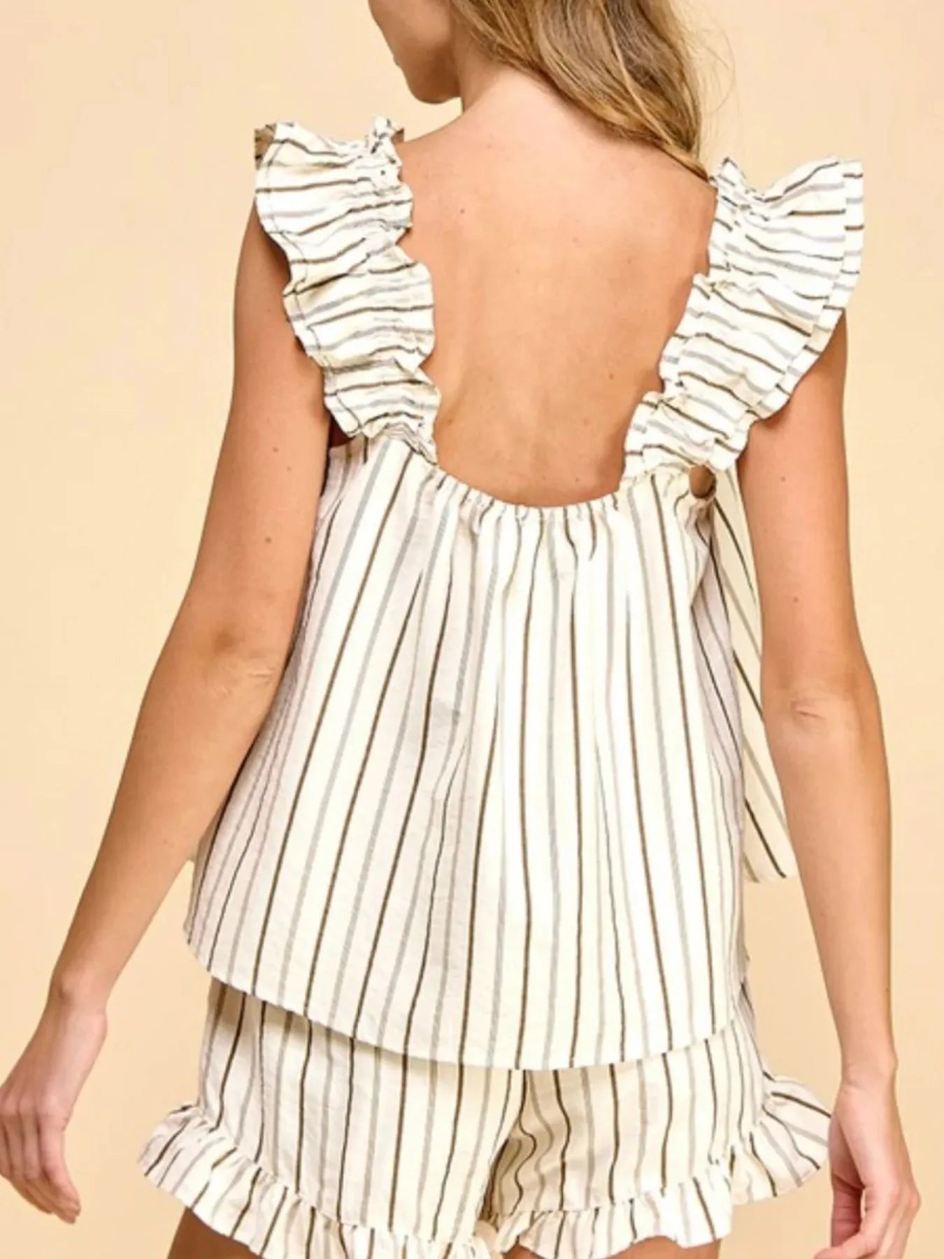 Woman wearing a striped dress with ruffled sleeves on a beige background