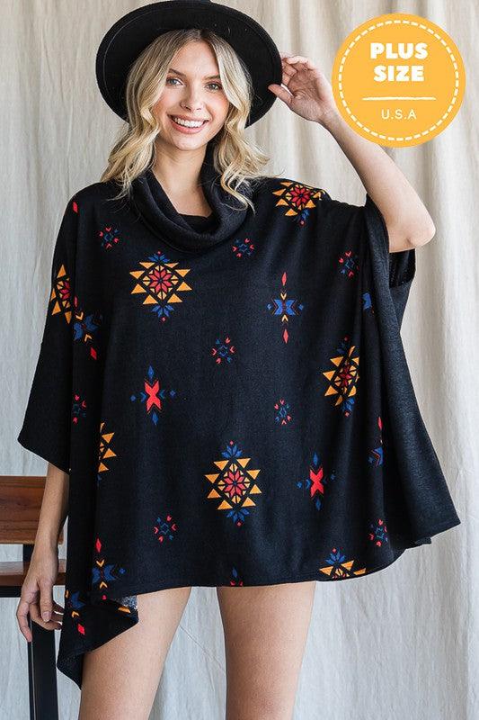 Woman wearing a black poncho with colorful patterns, standing against a neutral background.
