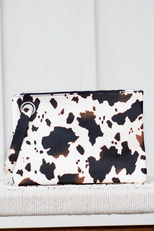 Clutch bag with cow print pattern on a white surface