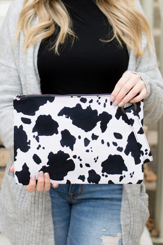 Person holding a black and white cow print pouch