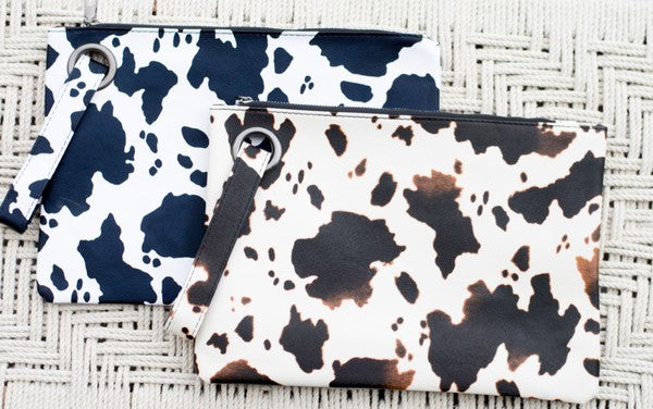 Two cow print bags on a textured surface
