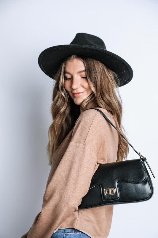 Woman wearing a black hat and holding a black handbag against a white background