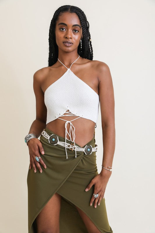 Woman wearing a white halter top and green skirt against a beige background