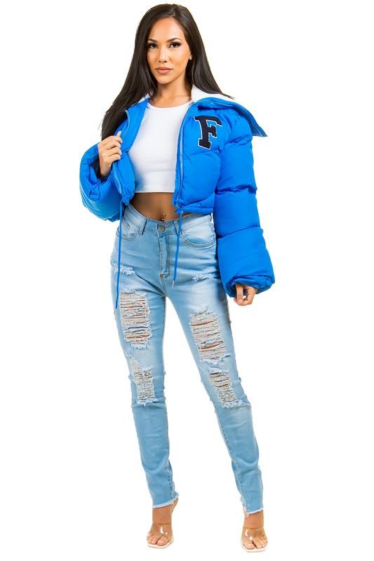 Woman wearing a blue puffer jacket and light blue jeans on a white background