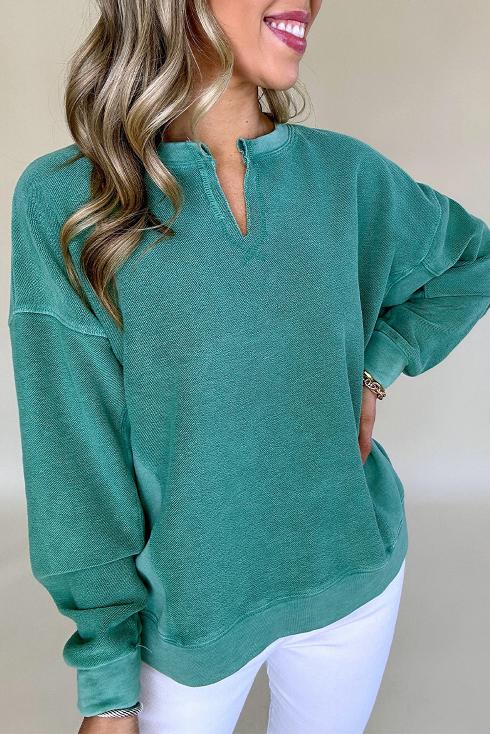 Person wearing a teal sweatshirt with a plain background