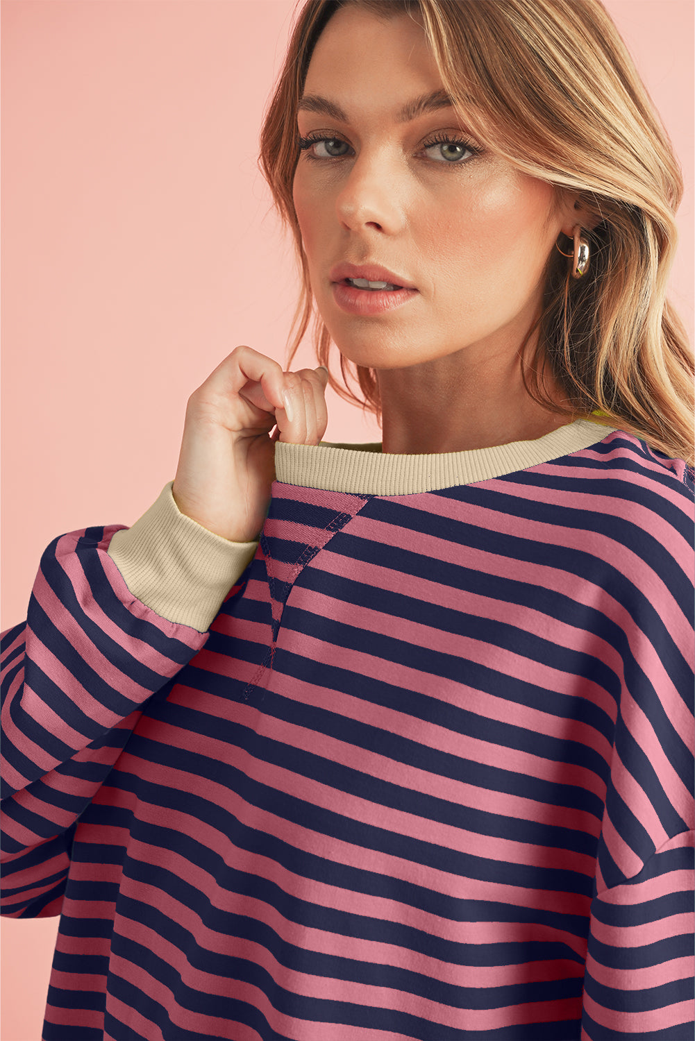 rson wearing a striped long-sleeve top and jeans on a pink background