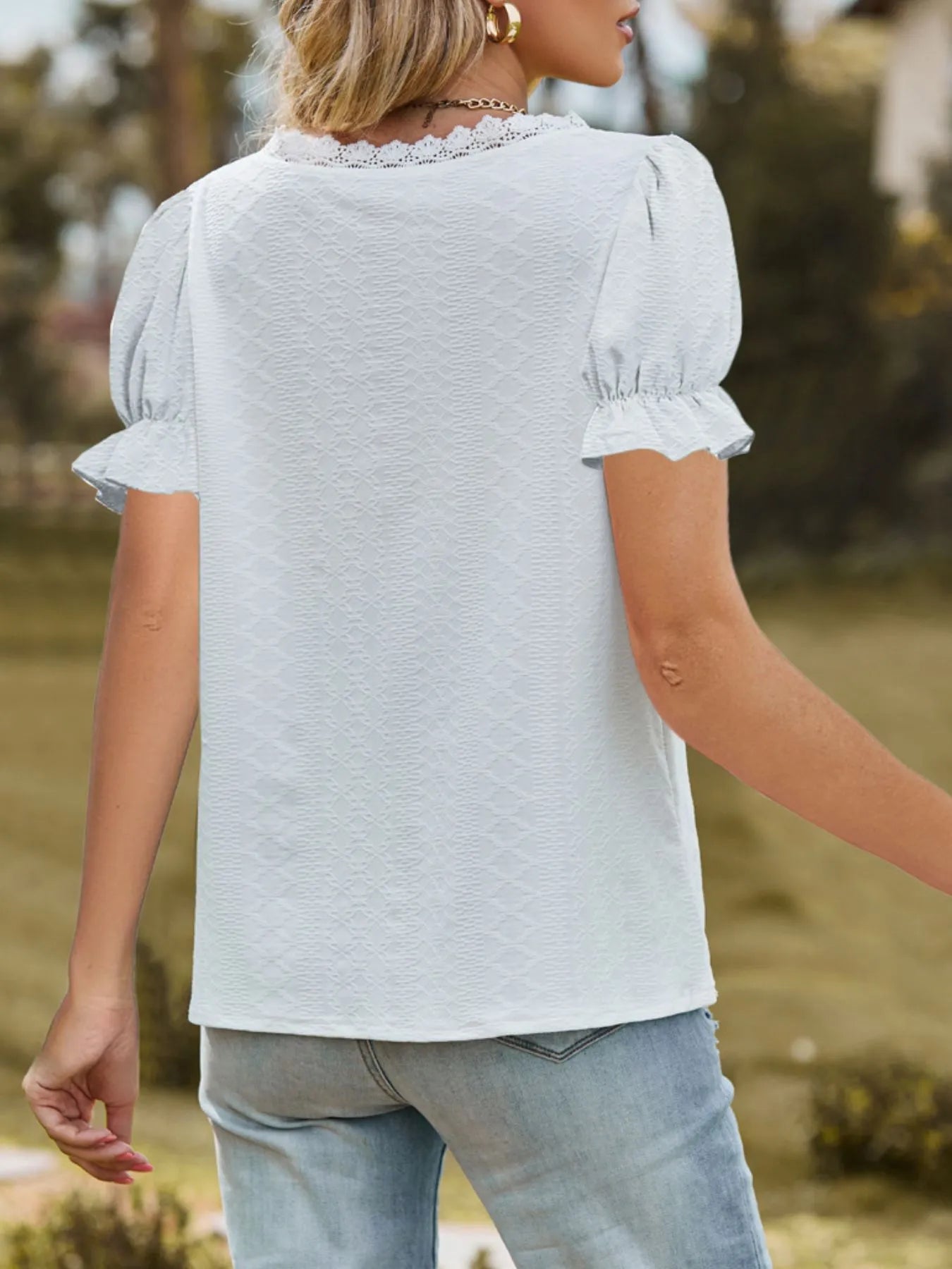 Person wearing a light blue blouse with ruffled sleeves in an outdoor setting