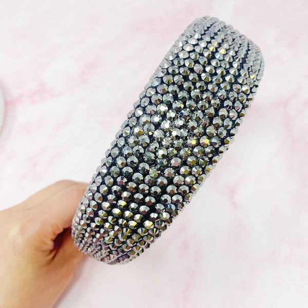 Hand holding a sparkling hair accessory against a pink background