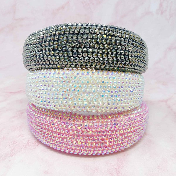 Stack of three crystal-embellished bracelets on a pink background