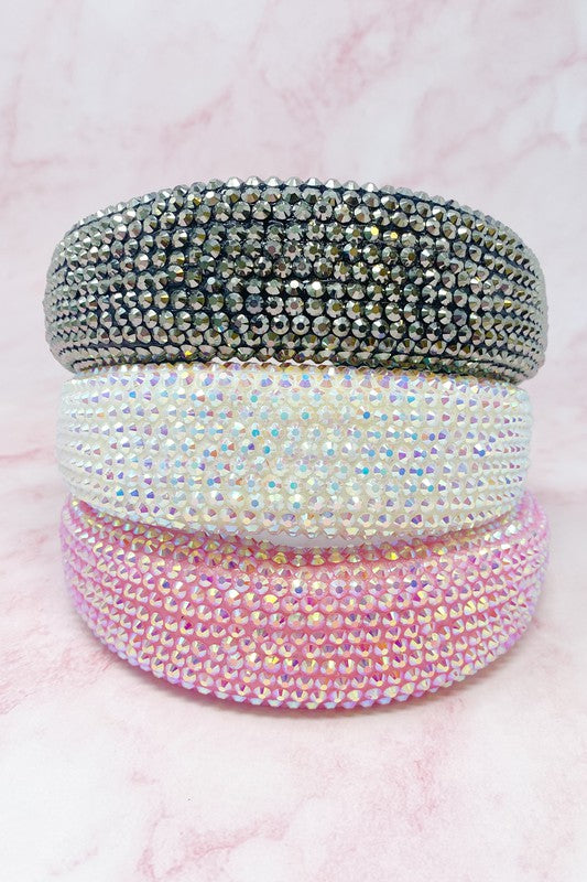 Three beaded hair ties in gray, white, and pink on a pink background