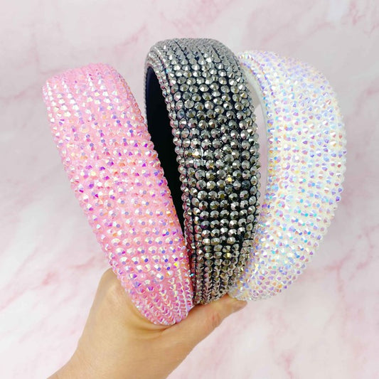 Three rhinestone headbands in pink, silver, and multicolor on a pink background.