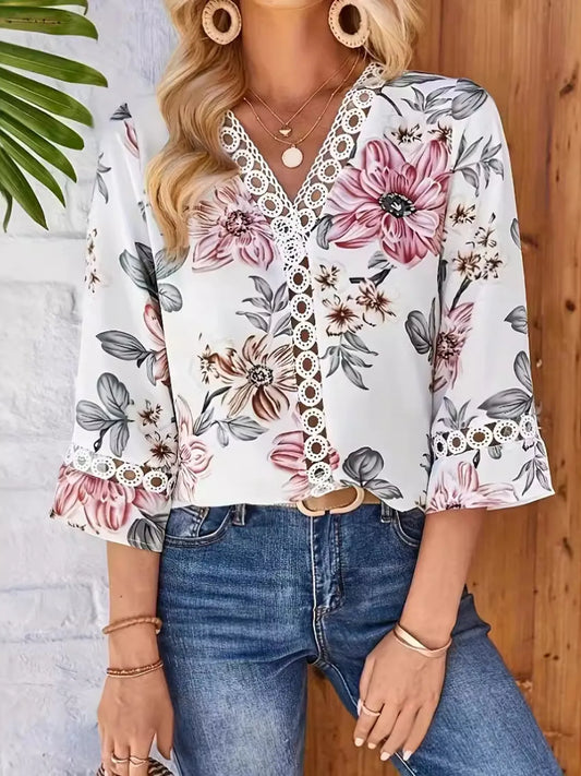 Woman wearing a floral blouse with lace details and blue jeans against a wooden wall.