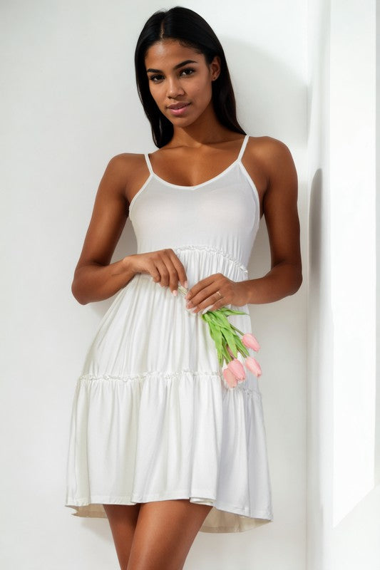 Woman wearing a white dress holding tulips against a plain background