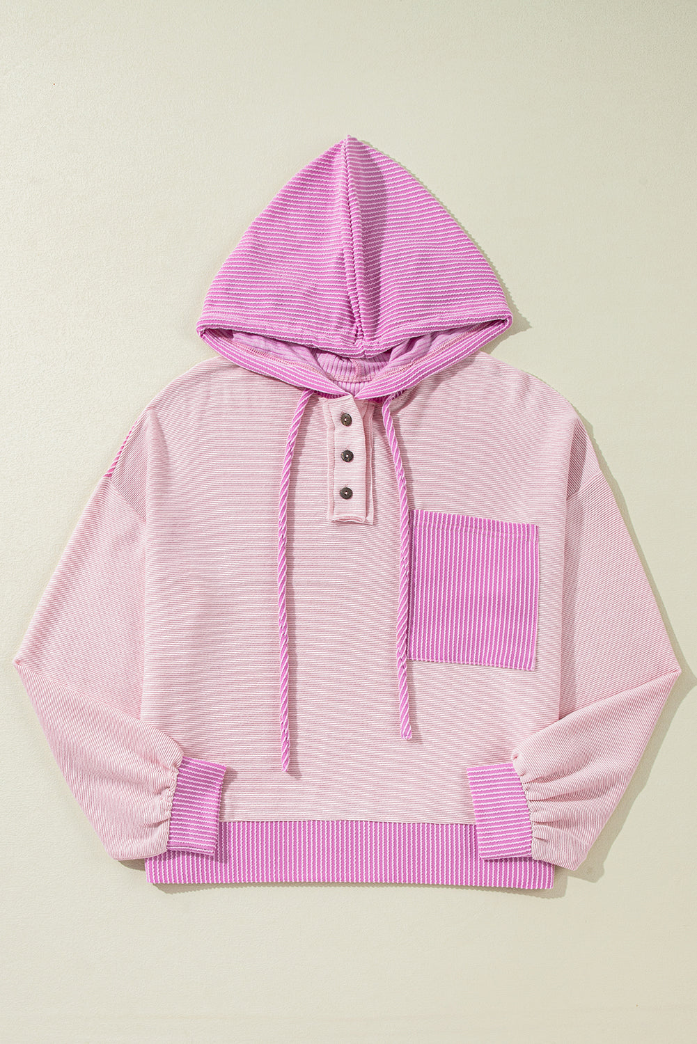 Pink hoodie with ribbed details on a light beige background