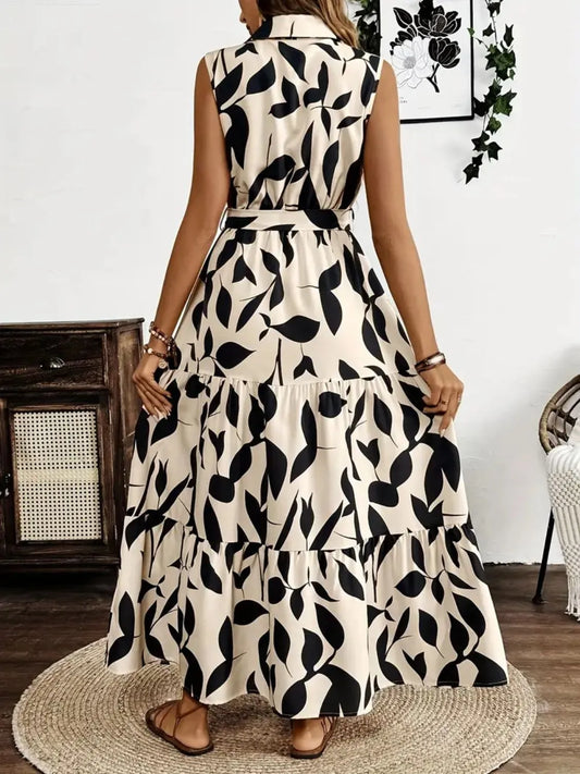 Woman wearing a sleeveless dress with black leaf pattern in a room.