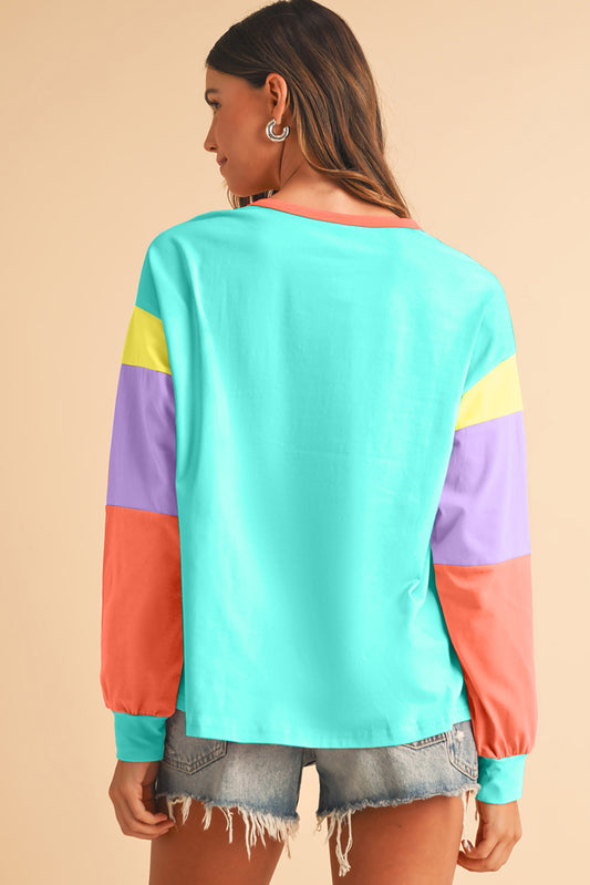 Woman wearing a colorful long-sleeve top with a beige background