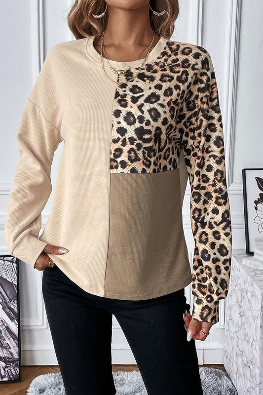 Beige and leopard print long-sleeve top worn by a person indoors.