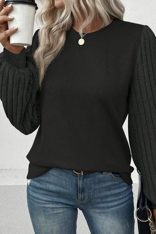 Person wearing a black sweater and blue jeans, holding a white cup.
