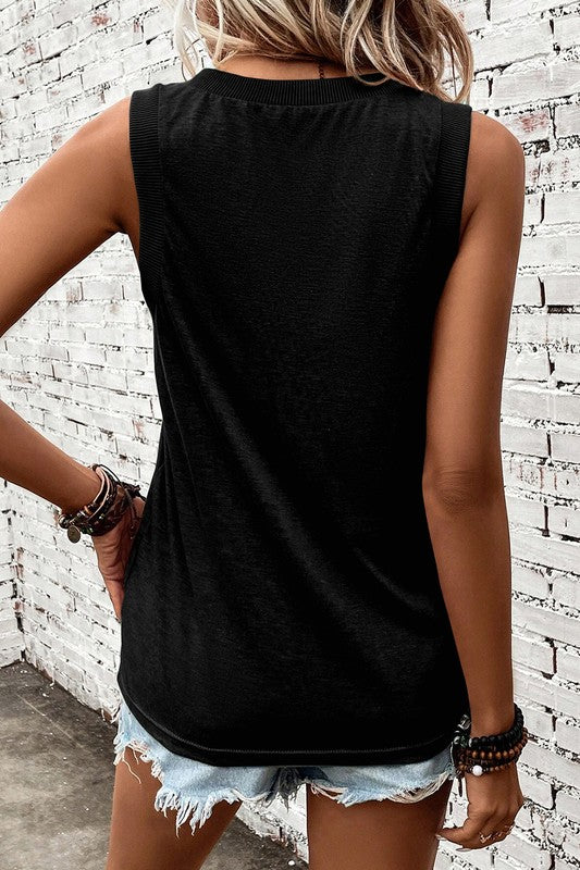 Person wearing a black sleeveless top and denim shorts against a white brick wall.