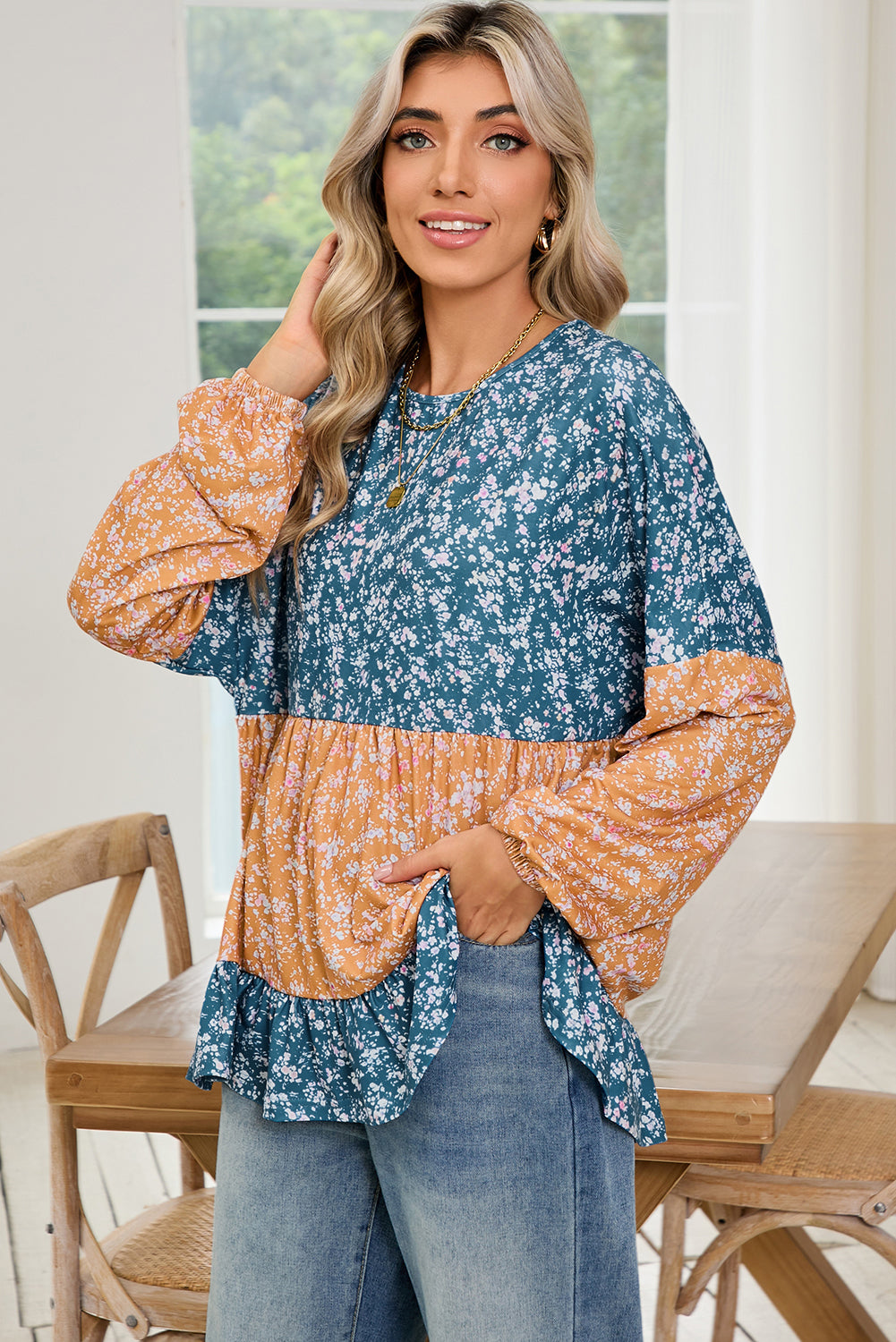 Woman wearing a floral blouse with a blue and orange pattern in a home setting.