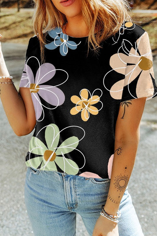 Person wearing a black t-shirt with colorful floral patterns and light blue jeans.