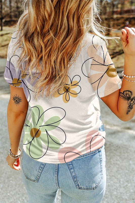 Person wearing a white t-shirt with colorful flower designs outdoors