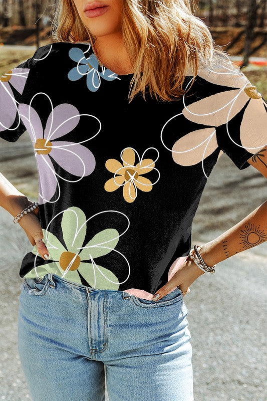 Person wearing a black t-shirt with colorful floral patterns and blue jeans.