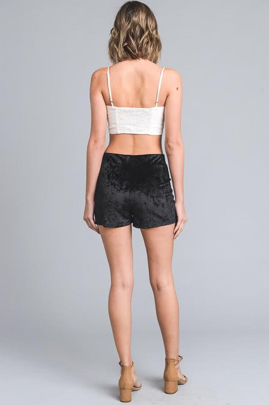 Woman wearing a white crop top and black shorts on a gray background