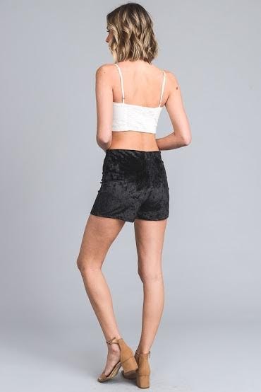 Woman wearing a white top and black shorts on a gray background