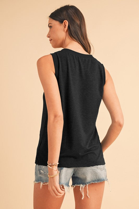 Woman wearing a black sleeveless top and denim shorts on a beige background